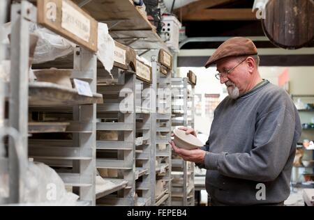 Potter indossando il tappo piatto in sala archiviazione controllo qualità incompiuta pentole di creta Foto Stock