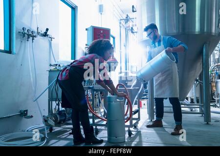 I colleghi nella fabbrica di birra da conica serbatoio di fermentazione di collegare tubo flessibile per taniche Foto Stock