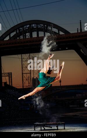 Ballerino femmina saltando mentre il rilascio di esplosione di polvere al tramonto, Los Angeles, Stati Uniti d'America Foto Stock