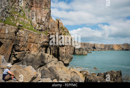 Turista femminile ammirando le scogliere a picco sul mare lungo la costa di Pembrokeshire nel Galles del Sud Foto Stock