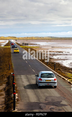 Vetture su strada rialzata che conduce a Isola Santa o Lindisfarne in Northumberland England Regno Unito che è tagliata fuori dal mare due volte al giorno Foto Stock