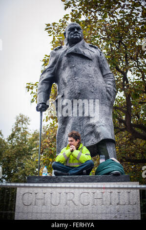 Anti-capitalista protester siede sulla statua di Churchill per 28 ore di stint contro gli ordini di polizia Foto Stock