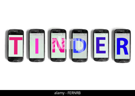 Tinder sugli schermi di smartphone fotografati contro uno sfondo bianco. Foto Stock