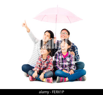 La famiglia felice seduto sotto un ombrello Foto Stock