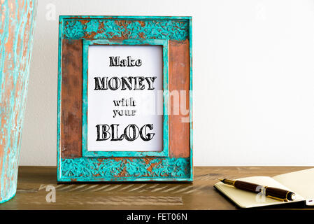 Vintage photo frame su un tavolo di legno oltre il muro bianco lo sfondo con il messaggio motivazionale per fare i soldi con il tuo blog Foto Stock