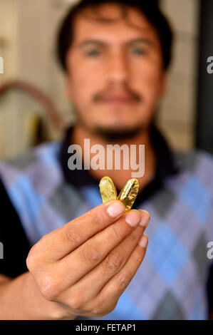 Uomo con due pezzi di oro in negozio, oro città mineraria di Laberinto, Puerto Maldonado, di Madre de Dios, Perù Foto Stock