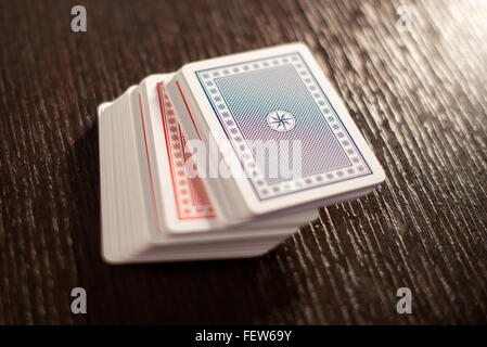 Mazzo di rosso e blu impilate le carte da gioco su un tavolo in legno con particolare attenzione alla scheda superiore e spazio di copia Foto Stock