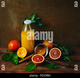 Ancora Vita con maturi succosa Agrumi sul tavolo in legno con bottiglia di succo di frutta appena spremuto. Colori vibranti, Quadrato Comp Foto Stock