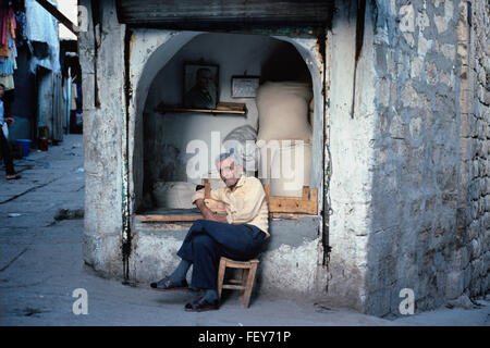 Negoziante di fronte al suo negozio di farina in stretti vicoli o strade della Città Vecchia Mardin, a sud-est della Turchia Foto Stock