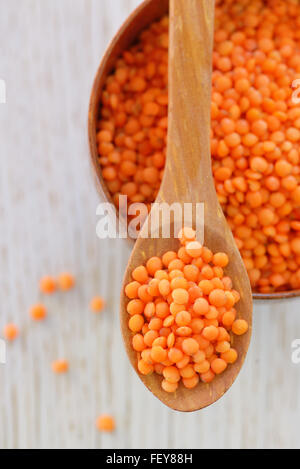 Di lenticchie rosse in cucchiaio su una tavola di legno Foto Stock