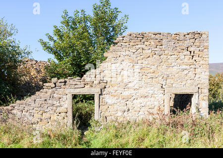 Rimane rovinato il vecchio edificio in pietra. Rovine nella campagna con alberi e di altri tipi di vegetazione che cresce dentro, vale di Edale, Derbyshire, England, Regno Unito Foto Stock