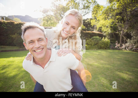 Il marito dando piggy back per moglie Foto Stock