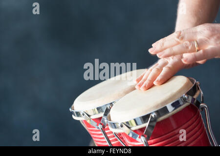 Mani playing red i tamburi di bongo con sfondo grigio Foto Stock