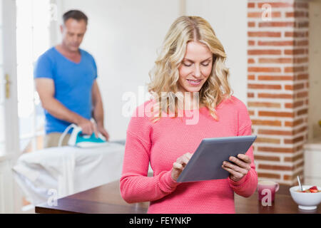 Donna che utilizza tablet mentre il marito utilizzando ferro Foto Stock