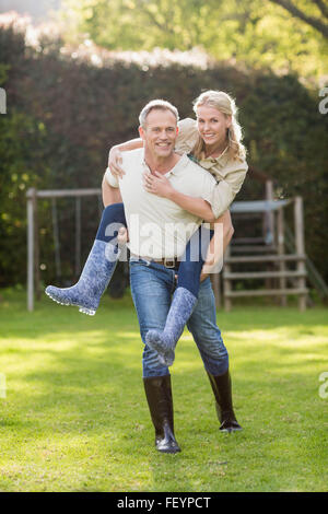 Il marito dando piggy back per moglie Foto Stock