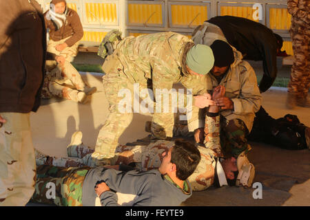 Membri della Royal Danish esercito, attaccato alla Task Force Al Asad, istruire le forze di sicurezza irachene in modo adeguato per verificare la presenza di un impulso durante un combattimento life saver corso di Al Asad Air Base, Iraq, Dic 29, 2015. Il corso è parte dell'edificio la capacità del partner (BPC) missione di addestramento, che include istruzioni sulla base di abilità di combattimento, tra cui tattiche militari, precisione di tiro, armi di manipolazione e contro-ordigni esplosivi artigianali. La missione di BPC mira ad aumentare la capacità militare delle forze locali di lotta contro lo Stato islamico dell Iraq e il levante. Foto Stock