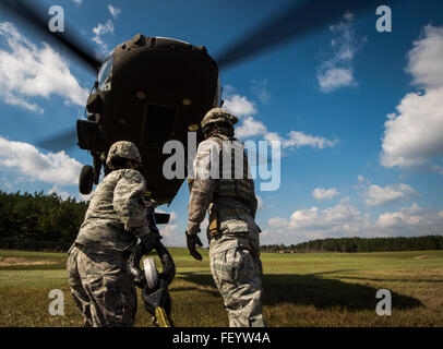 Stati Uniti Air Force aviatori da 321contingenza squadrone di risposta dal giunto di baseGuire-Dix Mc-Lago Hurst, N.J., provare a fissare una imbracatura di carico a un esercito di Mississippi Guardia Nazionale evacuazione medica UH-60 Black Hawk elicottero a Camp Shelby forze congiunte Training Center, Miss., durante l'esercizio di distribuzione Turbo, Ottobre 29, 2015. Gli Stati Uniti Il trasporto del comando test di esercizio la Joint Task Force Port-Opening è in grado di offrire e distribuire il carico durante l'assistenza umanitaria. Foto Stock