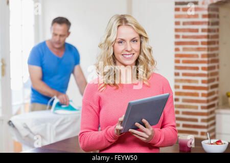 Donna che utilizza tablet mentre il marito utilizzando ferro Foto Stock