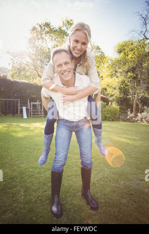 Il marito dando piggy back per moglie Foto Stock