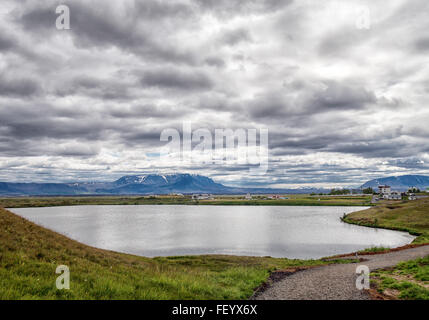 Nord Islanda Islanda. 1 agosto, 2015. Laguna Stakholstjorn visto dal sentiero della Skutustadagigar Pseudocrater zone umide del Nord Islanda vicino al Lago Myvatn. In fondo sono una tuya, un distintivo, flat-sormontato, ripide facciate vulcano e una fattoria. Popolari per il bird watching le zone umide sono conservati come una naturale area di conservazione. Il turismo è diventato un settore in crescita dell'economia e l'Islanda è diventata una destinazione turistica preferita. © Arnold Drapkin/ZUMA filo/Alamy Live News Foto Stock