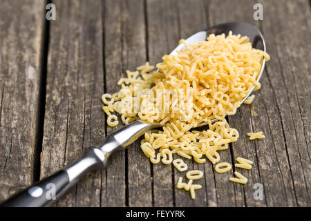 Alfabeto di pasta a cucchiaio sul vecchio tavolo in legno Foto Stock