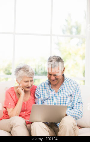 Sorridente coppia senior utilizzando laptop Foto Stock