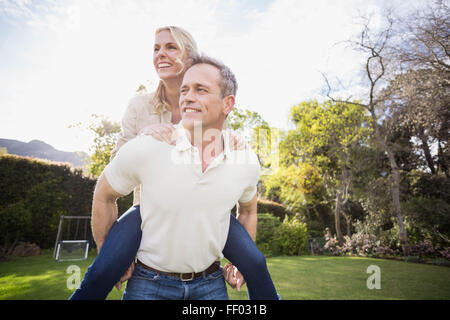 Il marito dando piggy back per moglie Foto Stock