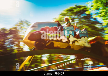 Le persone che si divertono sull Rollercoaster nel parco. Foto con Zoom sfocato per effetto di movimento Foto Stock