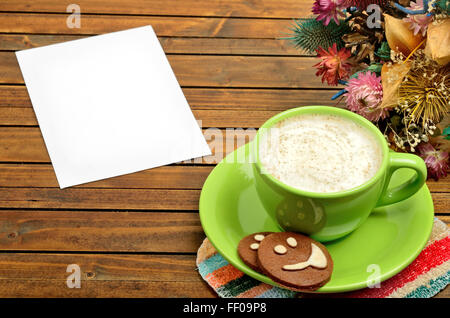Tazza di cappuccino con carta vuota sul tavolo di legno Foto Stock