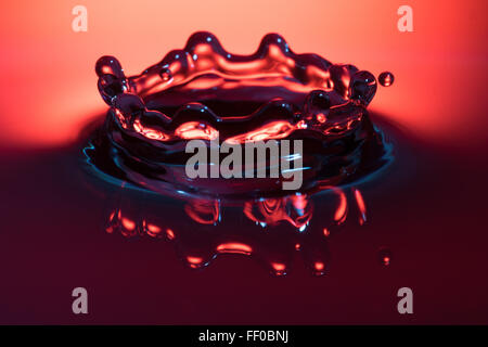 Una goccia di acqua che colpisce la superficie di un contenitore pieno di liquido Foto Stock
