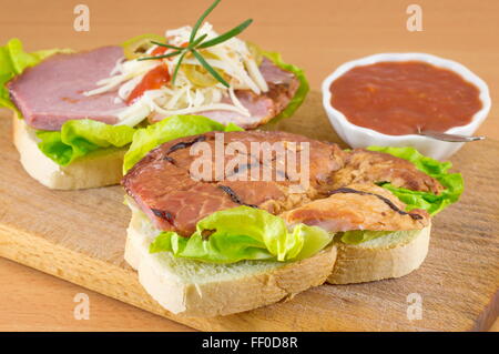 La realizzazione di una doppia panino su un tagliere Foto Stock