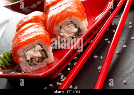 Rotoli di sushi con le bacchette di colore rosso su una tavola di ardesia. Foto Stock