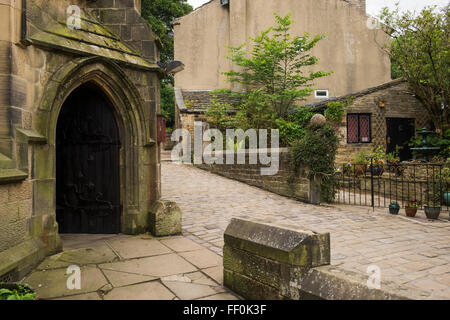 Acciottolato sulla corsia stretta (Chiesa Street) e porta arch, San Michele e Tutti gli Angeli Chiesa - Bronte il villaggio di Haworth, West Yorkshire, GB, UK. Foto Stock