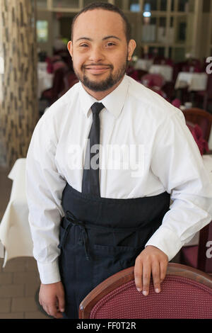 Razza mista server con la sindrome di down sorridente in ristorante Foto Stock