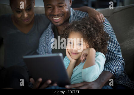 La famiglia tramite tavoletta digitale sul divano Foto Stock