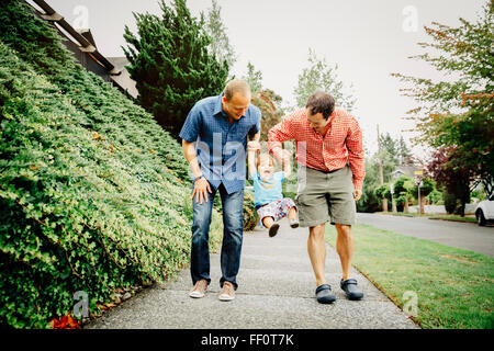 Gay padri giocando con il bambino figlio sul marciapiede Foto Stock