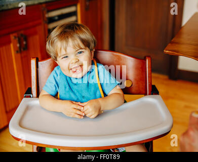 Baby boy ridere in sedia alta Foto Stock