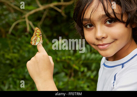 Razza mista boy holding butterfly Foto Stock