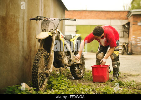 Uomo caucasico lavaggio dirt bike Foto Stock