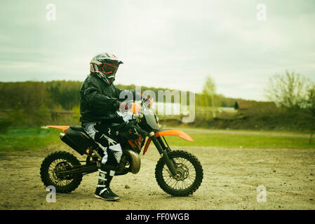 Uomo caucasico equitazione dirt bike nel campo Foto Stock