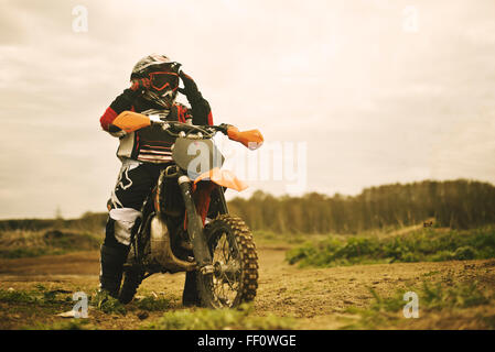 Uomo caucasico equitazione dirt bike nel campo Foto Stock