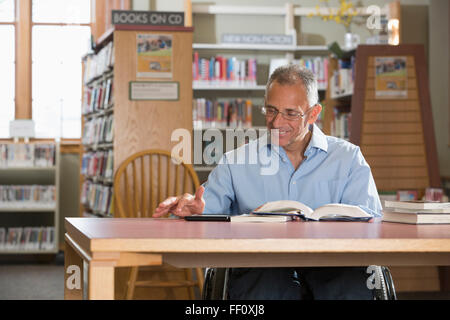 Uomo caucasico lettura in biblioteca Foto Stock
