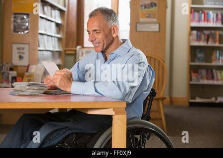 Uomo caucasico esaminando i DVD in biblioteca Foto Stock