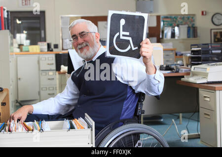 Imprenditore caucasico tenendo premuto segno di portatori di handicap in office Foto Stock