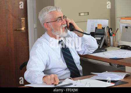 Imprenditore caucasico parlando al telefono in ufficio Foto Stock