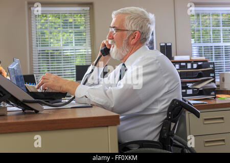 Imprenditore caucasico parlando al telefono alla scrivania Foto Stock