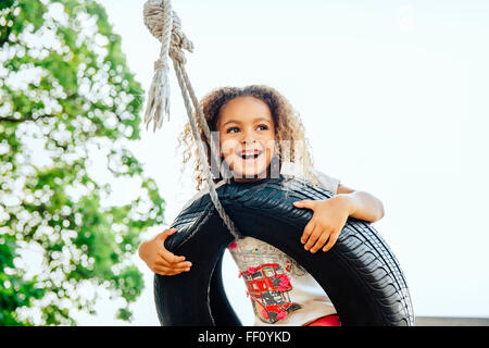 Razza mista ragazza sorridente in tire swing Foto Stock