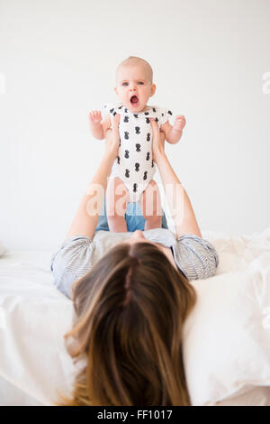 Madre caucasica tenendo la nostra bambina sul letto Foto Stock