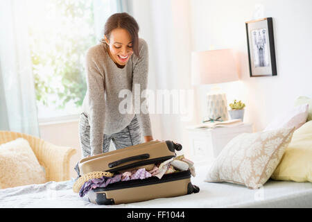 Razza mista donna valigia di imballaggio nel letto Foto Stock