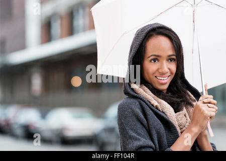 Razza mista donna ombrello porta all'aperto Foto Stock